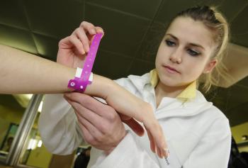 Zdravotná sestra upevňuje pacientovi identifikačný náramok
