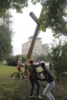Ukrajinskí podporovatelia Pussy Riot stínajú kríž osadený na počesť obetí politického utláčania