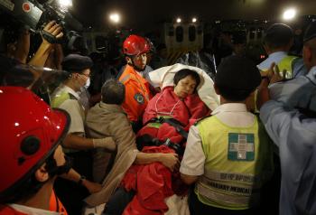 Záchranári prevážajú zachránenú pasažierku po kolízii dvoch lodí