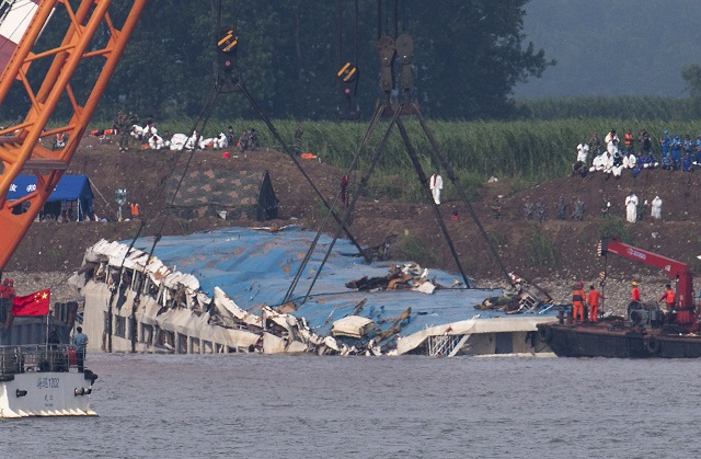 KK47 ien-li  - Na snímke obrátená výletná loï, ktorá sa potopila v rieke Jang-c'-iang v centrálnej èínskej provincii Hubej 5. júna 2015. Èínski záchranári obrátili výletnú úloï, ktorá sa v utorok 2. júna potopila v rieke Jang-c'-iang. Zo 460 cestujúcich sa podarilo zachráni 14 osôb. FOTO TASR/AP Rescuers use cranes to lift the capsized ship Eastern Star on the Yangtze River in Jianli county of southern Chinas Hubei province, as seen from across the river from Huarong county of southern Chinas Hunan province, Friday, June 5, 2015. The Eastern Star's top-deck cabins with smashed blue roofs jutted out of gray water Friday after Chinese disaster teams righted the capsized river cruiser to ease the search for people still missing. (AP Photo/Andy Wong)
