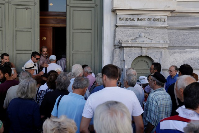 Na snímke prví zákazníci  - väčšinou dôchodcovia -  čakajú v rade pred sídlom gréckej národnej banky v Aténach