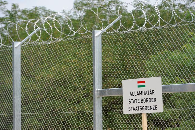 Na snímke tabuľa s nápisom štátna hranice sa nachádza pred dokončeným  175-metrovým skúšobným úsekom dočasnej zábrany na maďarsko-srbských hraniciach