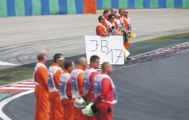Traťoví komisári držia transparent s iniciálkami a číslom 17 zosnulého francúzskeho jazdca formuly 1 Julesa Bianchiho počas minúty ticha na jeho počesť pred štartom nedeľňajších pretekov Veľkej ceny Maďarska v Budapešti 26. júla 2015