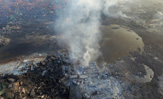 Na leteckej snímke stúpa dym z trosiek kontajnerov pri kráteri v epicentre série zničujúcich výbuchov v čínskom prístave Tchien-ťin