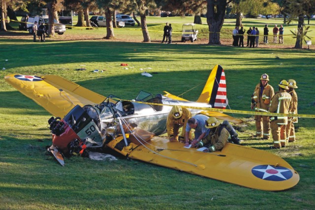 Na archívnej snímke z 5. marca 2015 vyšetrovatelia a hasiči obhliadajú lietadlo herca Harrisona Forda, ktorý havaroval na golfovom ihrisku vo Venice pri Los Angeles. Príčinou havárie historického lietadla bola porucha karburátora