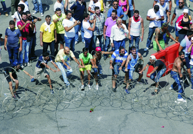 Aktivisti odstraňujú ostnatý drôt pred budovou vlády počas protestu  kvôli neschopnosti vlády riešiť aktuálny problém s odvozom ton odpadkov, ktoré smetiari už niekoľko týždňov neodvážajú z Bejrútu