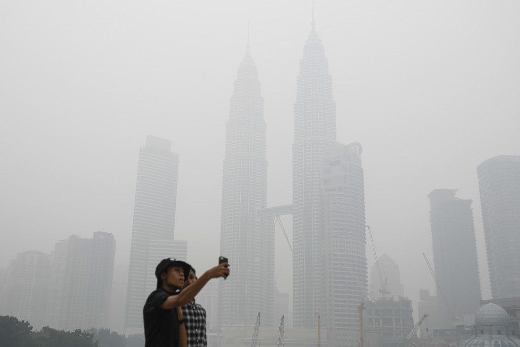 Na archívnej snímke sa turisti fotia selfie so smogom v meste v pozadí  s budovami