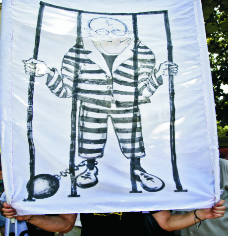 Na archívnej snímke z 13. júna 2010 muž drží transparent s podobizňou rumunského exprezidenta Iona Illiesca počas  protestu, na ktorom demonštranti požadovali vyvodenie zodpovedať z údajného spáchania zločinov proti ľudskosti pri potlačení protivládnych protestov pred 20 rokmi