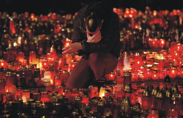 Na archívnej snímke mladík zapaľuje sviečku na pamiatku obetí  požiaru pred nočným klubom Colectiv v Bukurešti
