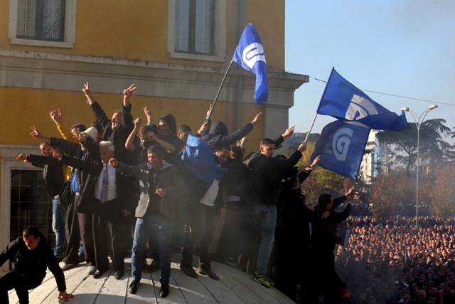 Stúpenci albánskej opozície stoja na bunkri počas protestu v Tirane