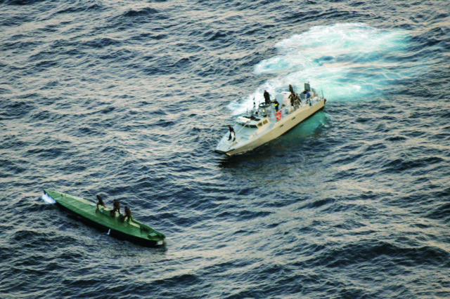 Na snímke členovia námornej pobrežnej hliadky plávajú smerom k zadržanej pašeráckej ponorke s drogovým kontrabandom po tom, ako ju odtiahli