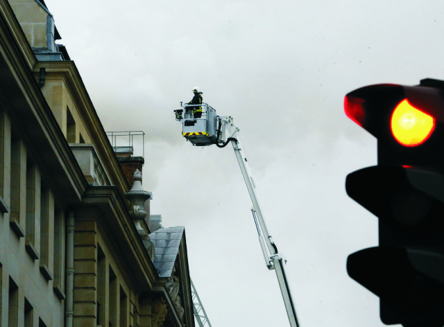 asič na požiarnom rebríku sa snaží dostať ku streche luxusného hotela Ritz počas požiaru v Paríži