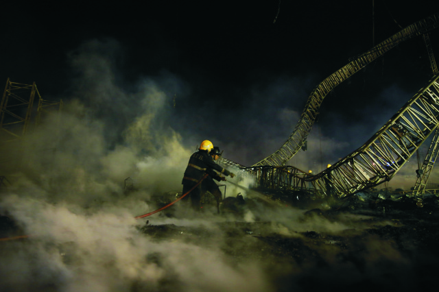 Na snímke indickí požiarníci  uhášajú zvyšky po mohutnom požiari