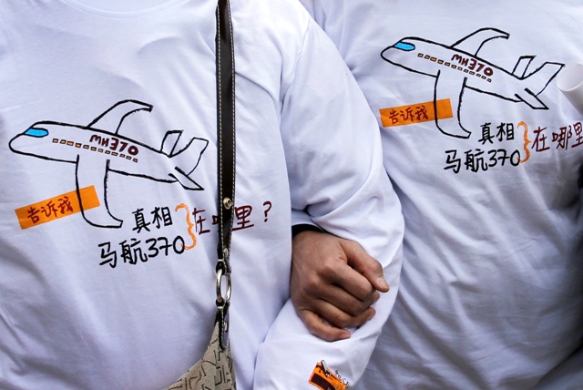 Na snímke príbuzní čínskych pasažierov nezvestného letu MH370 malajzijskej leteckej spoločnosti Malaysia Airlines stoja v tričkách s odkazom pre let MH370 v Pekingu