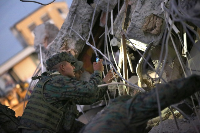 Vojak si svieti mobilom počas pátrania po preživších v troskách zrútenej budovy po silnom zemetrasení s magnitúdou 7,8 na ulici v Portovieju