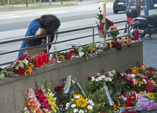 Na snímke žena smúti na mieste plnom kvetov a sviečok, kde v piatok zastrelil 18-ročný iránsky imigrant s nemeckým a iránskym občianstvom 10 ľudí vrátane seba v mníchovskom McDonalde a nákupnom centre v nedeľu 24. júla 2016. 