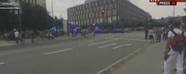 Na snímke z videa policajné jednotky a ľudia pred obchodným centrom, kde sa strieľa