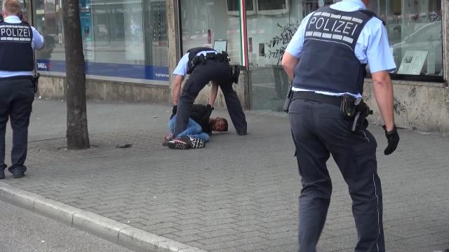 Na snímke nemeckí policajti zatýkajú sýrskeho muža, ktorý mačetou zabil na zastávke ženu a dvoch ľudí zranil v nemeckom meste Reutilingen