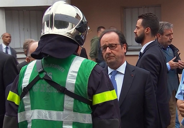 Na snímke francúzsky prezident Francois Hollande sa rozpráva s hasičom po príchode do francúzskeho mesta Saint-Étienne-du-Rouvray, v ktorom útočníci podrezali 84-ročného kňaza v miestnom kostole počas rukojemníckej drámy v utorok 26. júla 2016