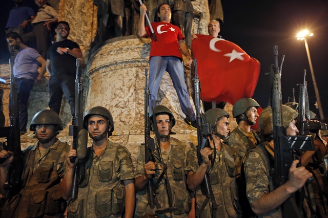 Tureckí vojaci stoja pred stúpencami prezidenta Recepa Tayyipa Erdogana počas protestu v Istanbule na námestí Taksim v sobotu 16. júla 2016