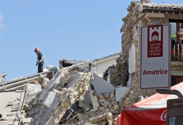 Hasič stojí na sutinách domu v meste Amatrice po otrasoch v strednom Taliansku