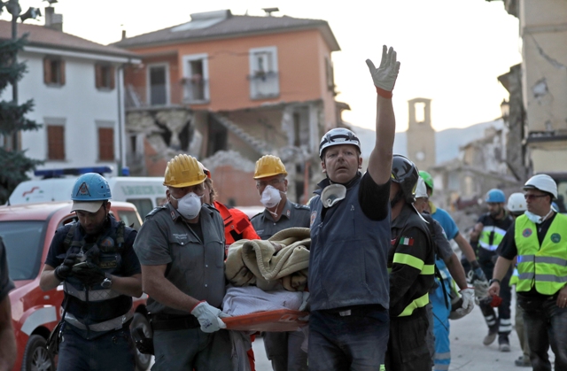 Záchranári vynášajú na nosidlách  telo pri prehľadávaní trosiek zrútenej budovy po zemetrasení v meste Amatrice, v centrálnom Taliansku Foto:TASR/AP-Alessandra Tarantino