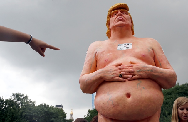 Žena ukazuje prstom na sochu nahého republikánskeho kandidáta na post prezidenta USA Donalda Trumpa, ktorá sa objavila vo štvrtok 18. augusta 2016 na manhattanskom námestí Union Square v New Yorku
