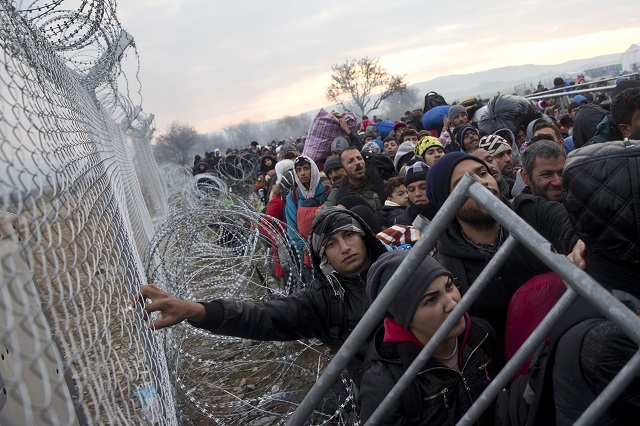 Ilustračné foto: Na snímke migranti a utečenci čakajú pri plote na grécko-macedónskej hranici v snahe prejsť do Macedónska v Idomeni