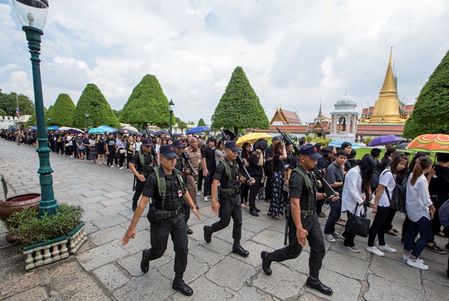 Thajskí vojaci kráčajú okolo smútiaceho davu v čiernom, ktorý prichádza vzdať hold zosnulému thajskému kráľovi