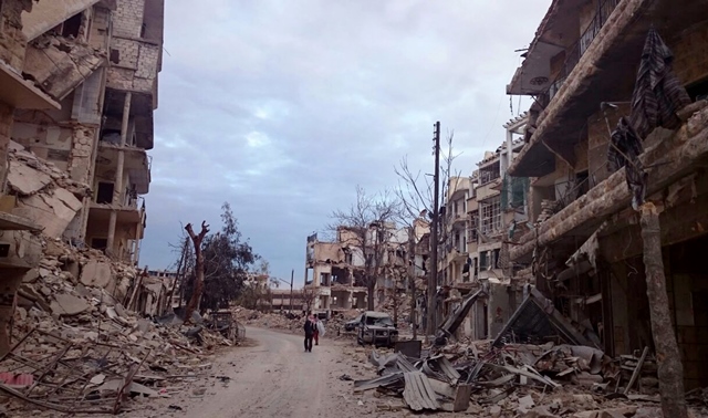 Na snímke muži kráčajú okolo zničených budov a obchodov počas bojov sýrskej vládnych síl s povstalcami vo východnej časti sýrskeho mesta Aleppo