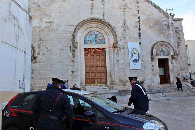 Talianski policajti, carabinieri stoja pred vchodom kostola Matky, kde by sa údajne mala konať bohoslužba na pamiatku bossa kanadského zločineckého klanu Rocco Sollecito v dedine Grumo Appula, pri meste Bari na juhu Talianska