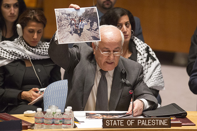 Palestínsky pozorovateľ pri OSN Rijád Mansúr ukazuje fotografiu z bojov medzi medzi Izraelom a militantmi Hamasu, ktorí kontrolujú pásmo Gazy počas zasadnutia Bezpečnostnej rady OSN