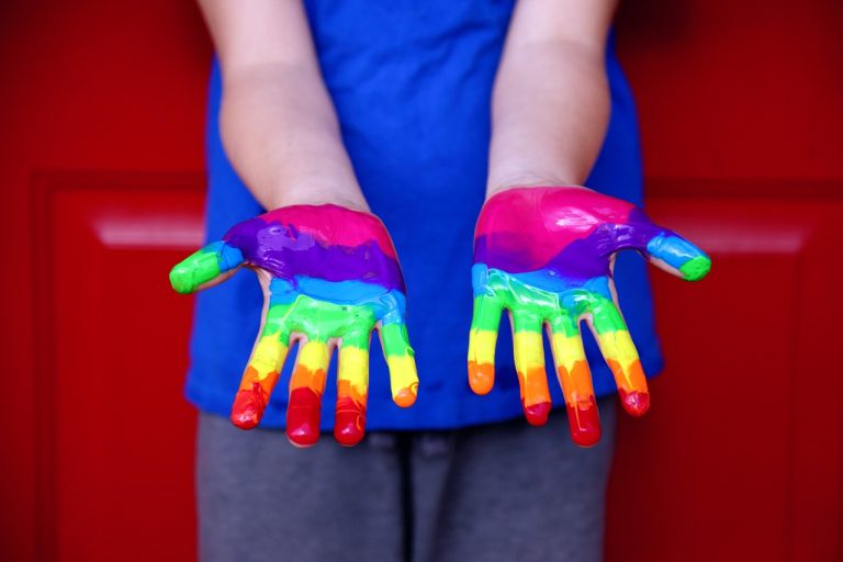 Dieťa s dúhovými farbami na rukách